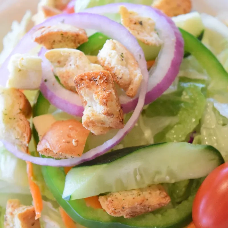 Fresh garden salad with lettuce, onions, peppers, carrots, tomatoes, and croutons.