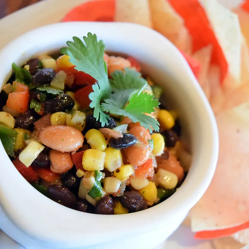 Colorful bean and corn salsa with cilantro and tortilla chips.