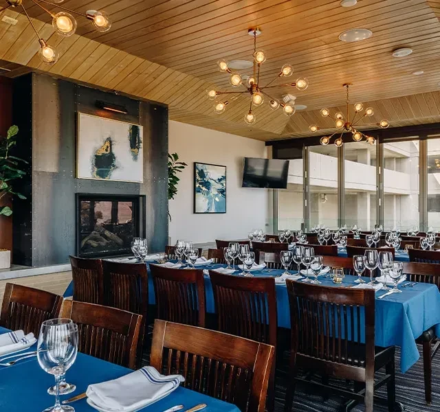 Modern dining room with set tables, Sputnik chandeliers, and a fireplace.