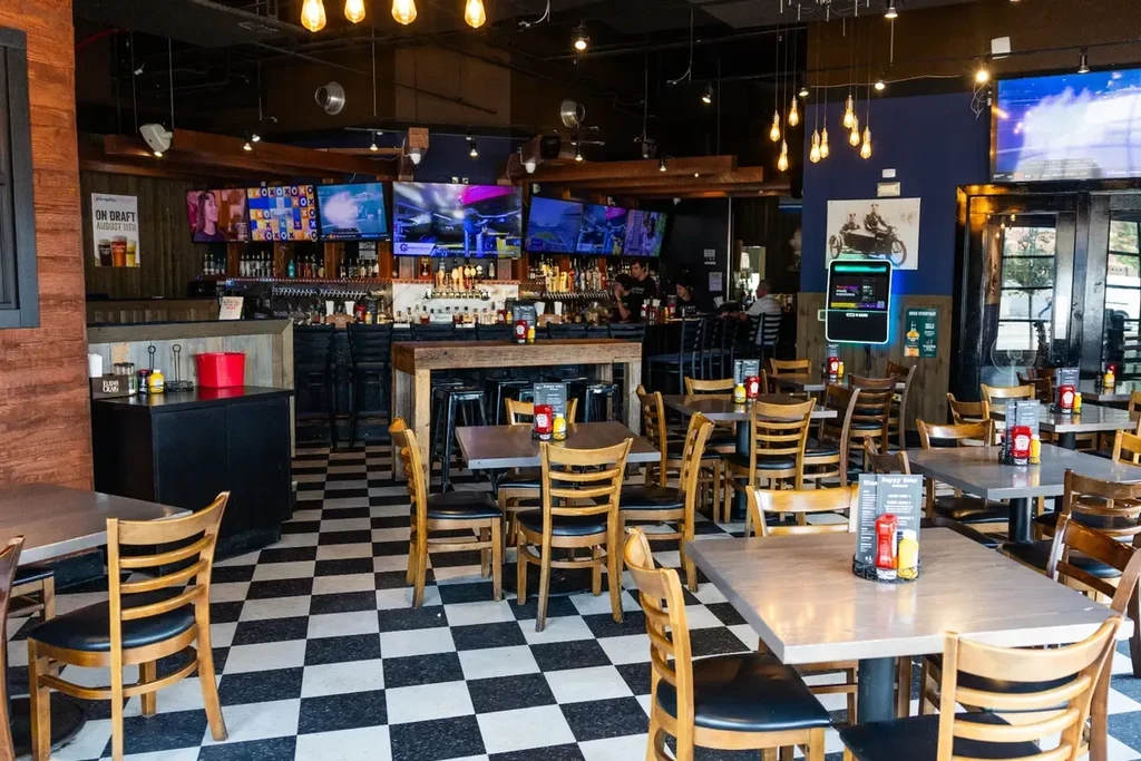 Modern sports bar with dining area, full bar, and TVs.