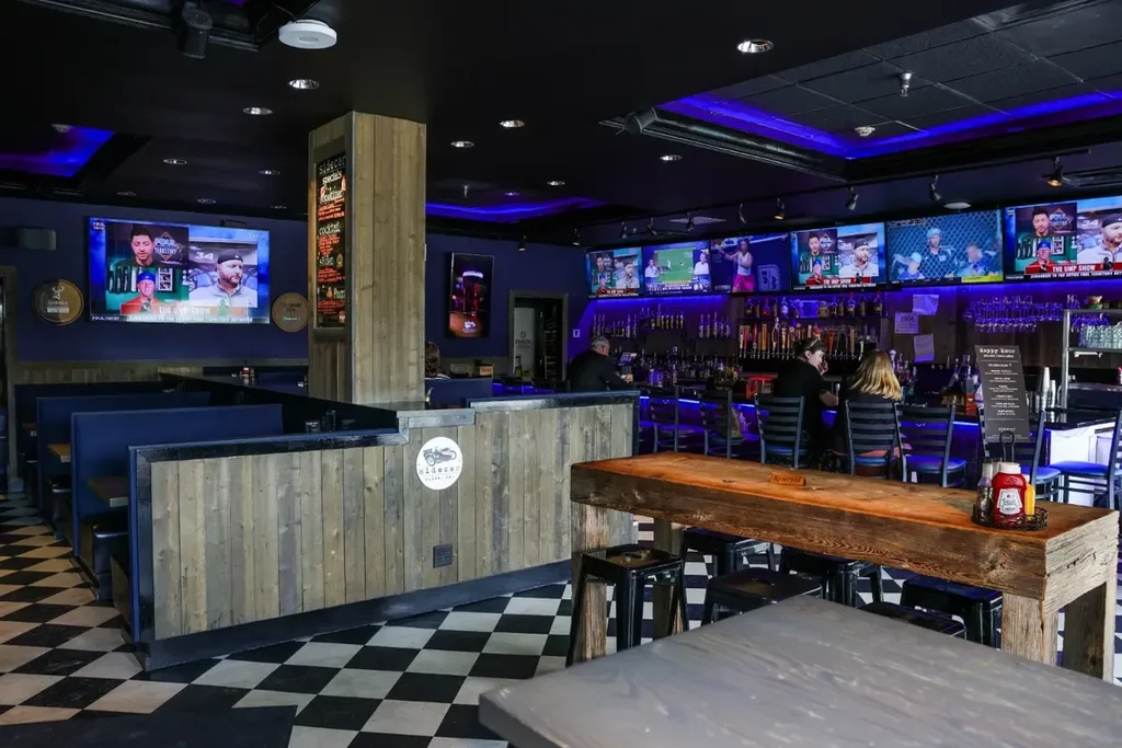 Sidecar sports bar interior with blue lighting and checkerboard floor.