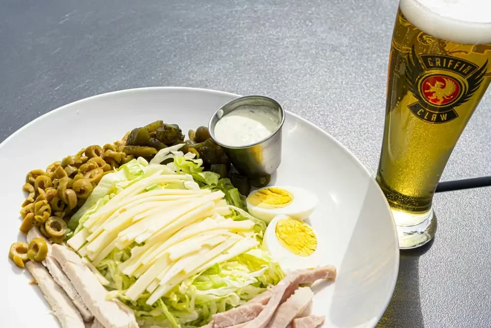 Hearty salad with chicken, eggs, olives, and a pilsner.