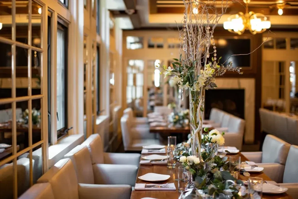 Long elegant dining table set with white flowers and crystals.