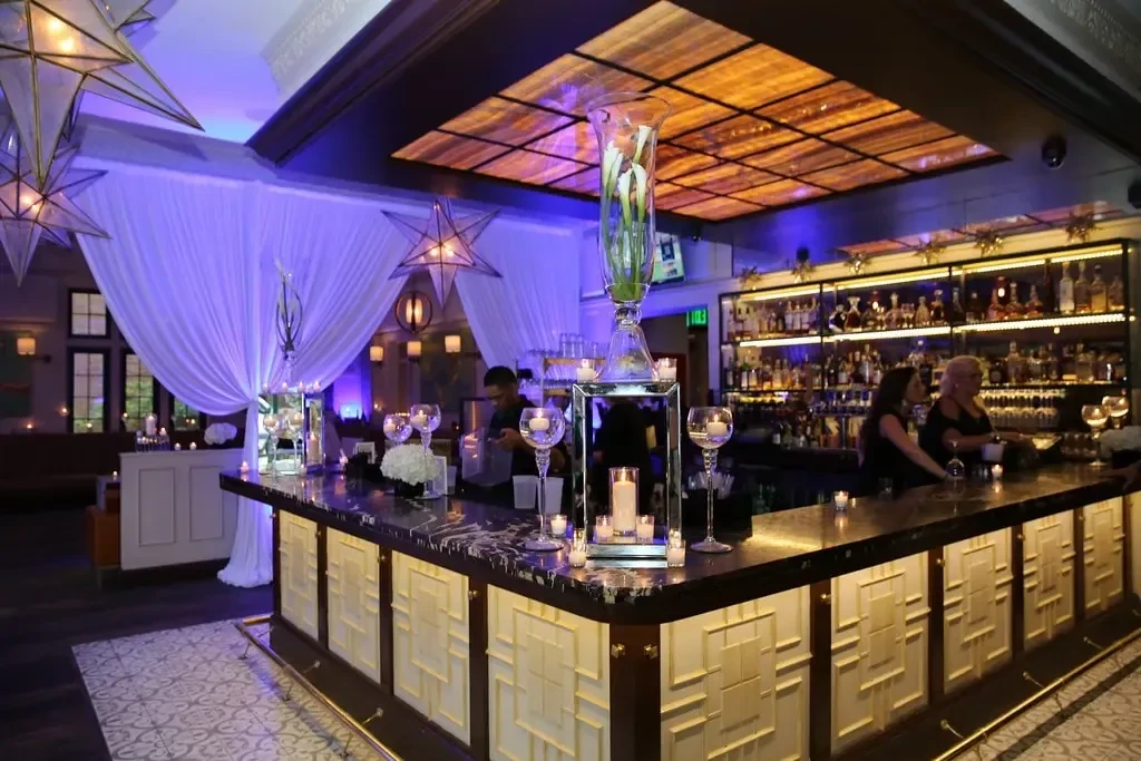 Elaborately decorated, well-stocked bar with dramatic lighting, flowers, and candles.