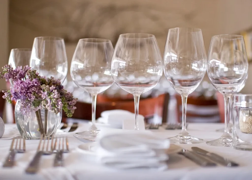 Empty wine glasses and purple lilacs on a set restaurant table.