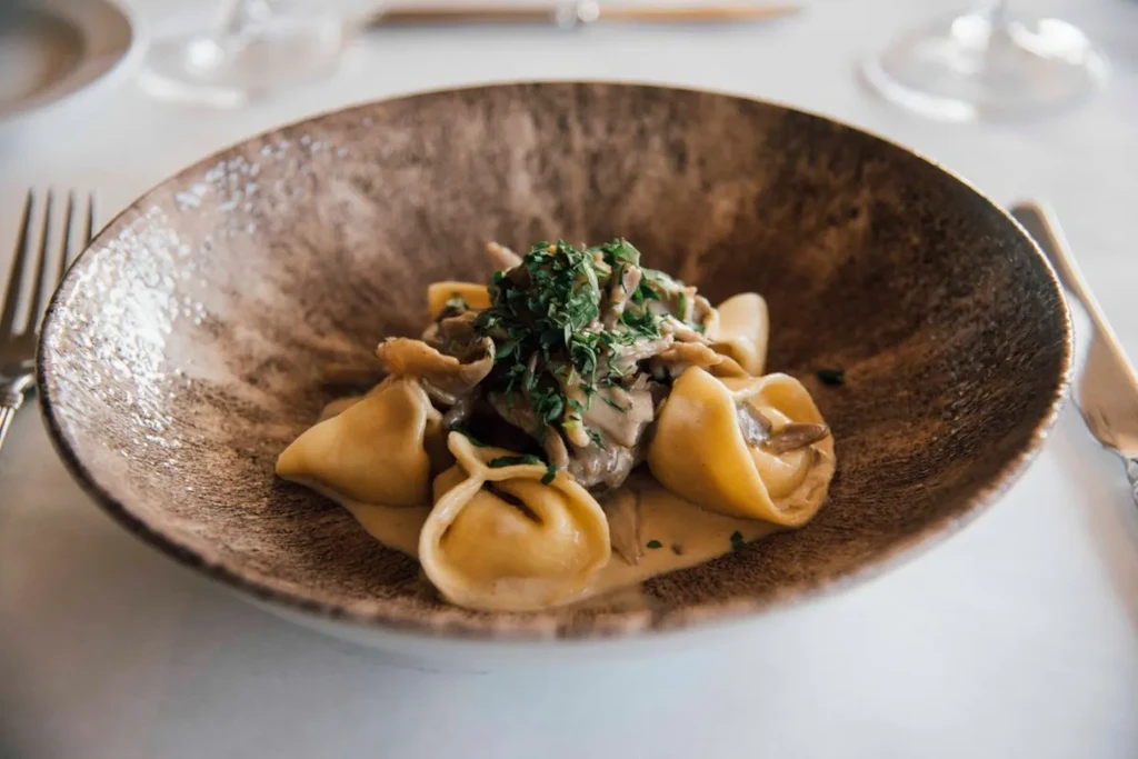 Creamy stuffed pasta with mushrooms and herbs, elegant dining background.