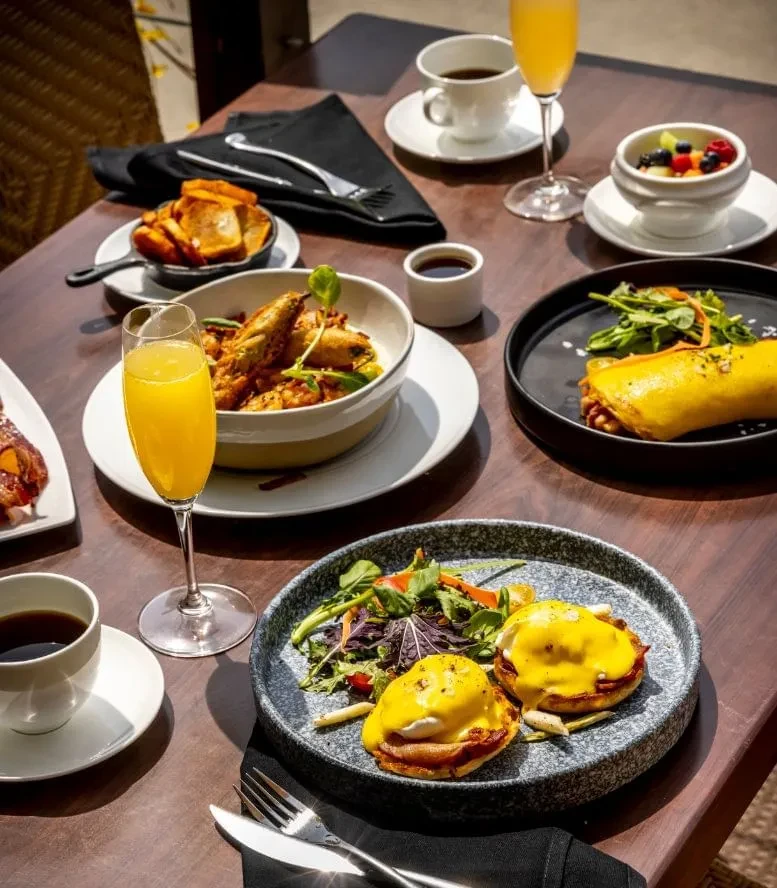 Bright, elegant brunch spread with Eggs Benedict, coffee, and mimosas.