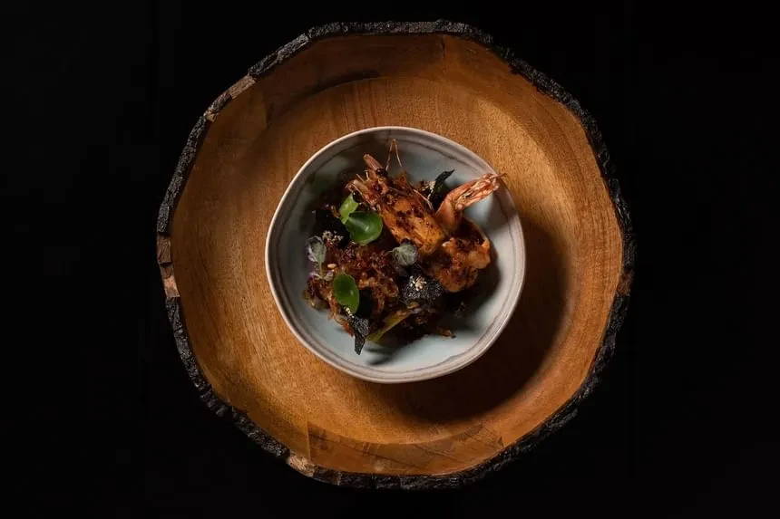Grilled shrimp with dark crispy bed, fresh greens in two bowls.