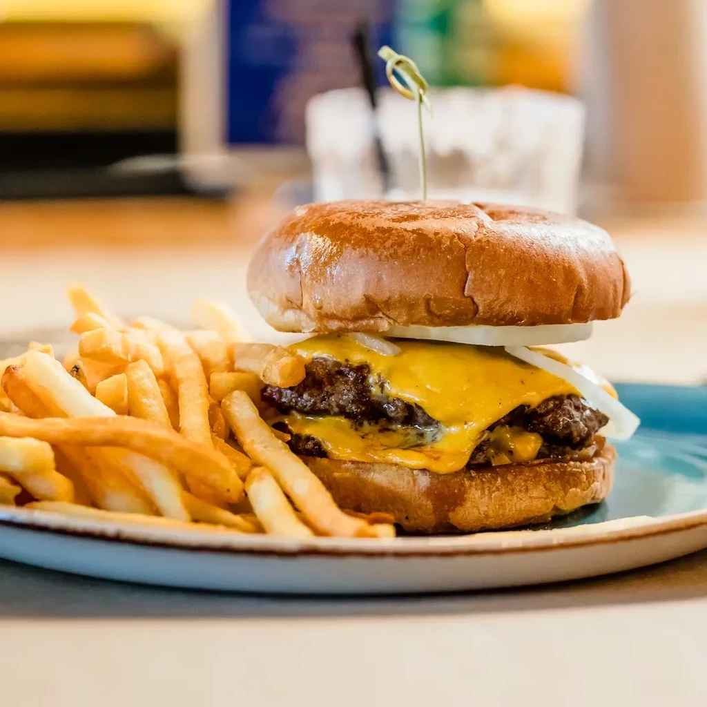 Double cheeseburger and crispy fries on a rustic blue plate.