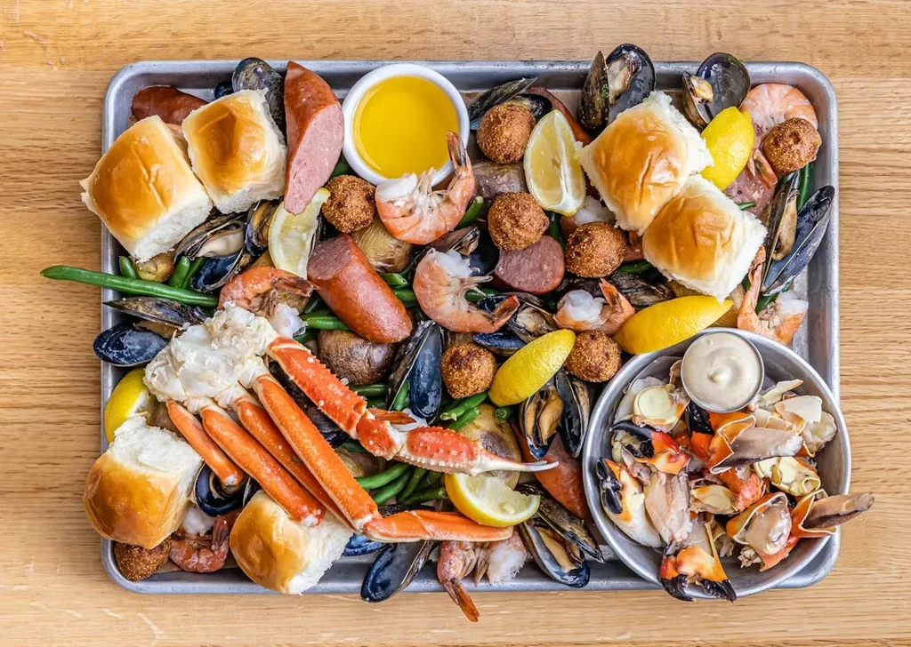 Overflowing seafood boil with crab, shrimp, sausage, vegetables, and sauces.