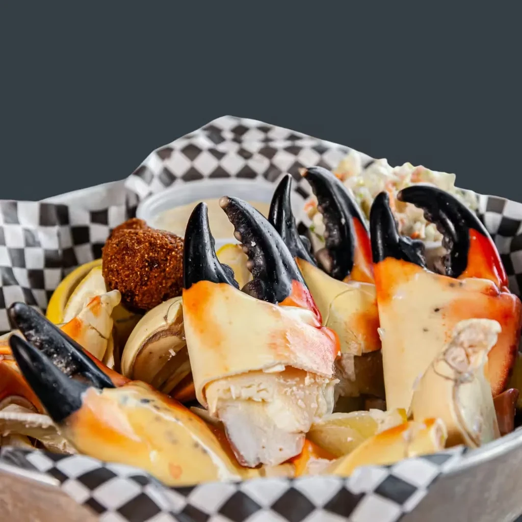 Cooked stone crab claws with lemon, coleslaw, and dipping sauce.