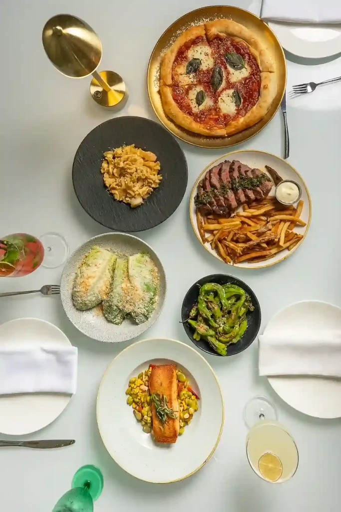 Overhead view of a modern restaurant table laden with various dishes and cocktails.