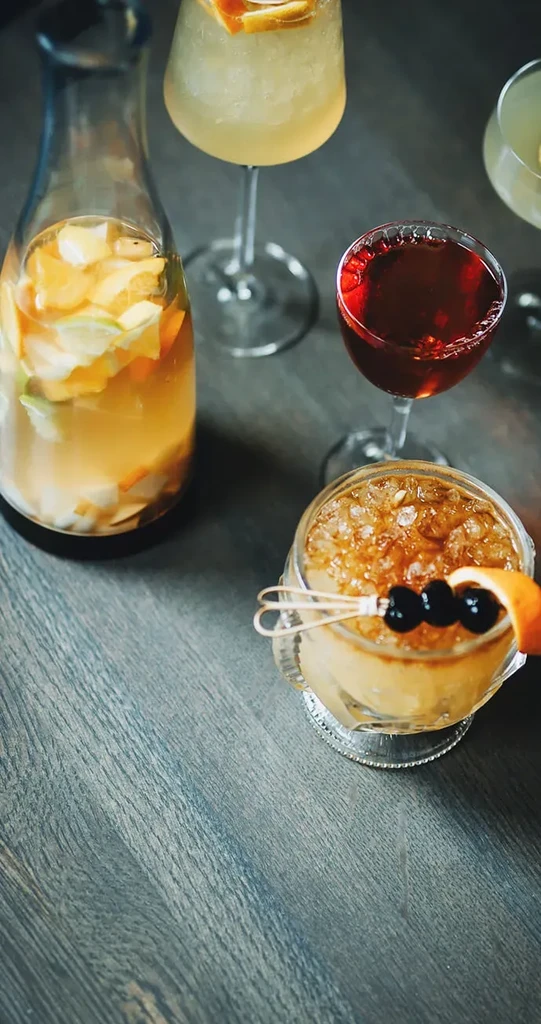 Four distinct, garnished beverages on a dark wooden table.