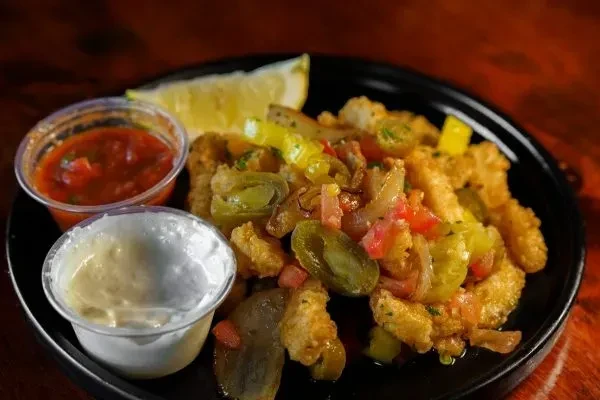 Fried calamari, colorful sautéed vegetables, lemon, and two dips.
