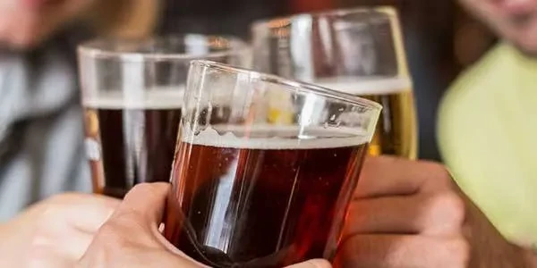 Close-up: Three hands holding glasses of beer in a toast.