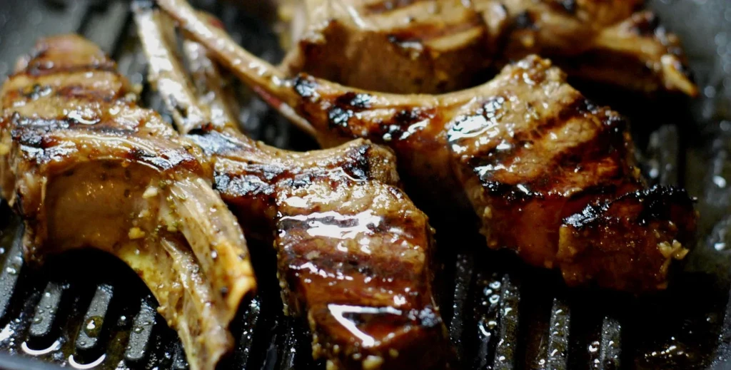 Well-seared meat chops with dark grill marks on a ridged pan.