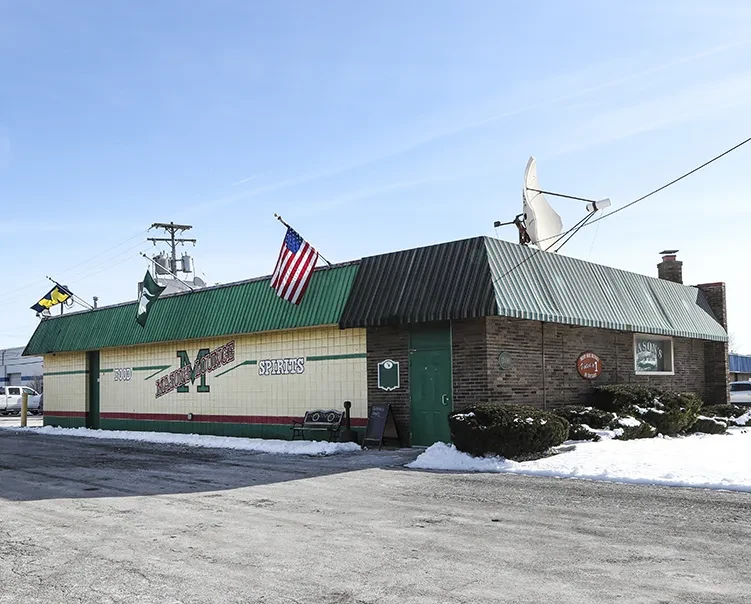 Single-story Mason Lounge building with flags, satellite dish, snow.