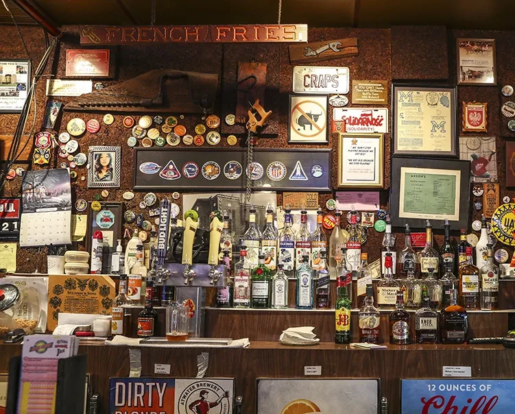 Rustic, well-stocked bar with spirits, beer taps, and cluttered wall decorations.