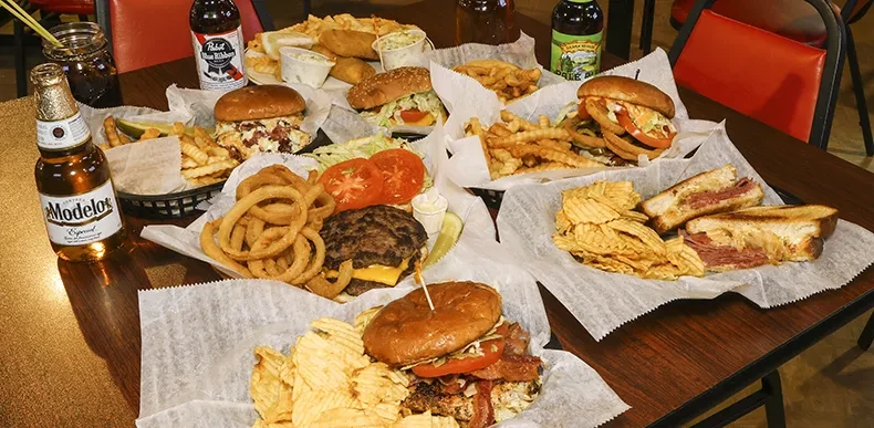 A table filled with burgers, fries, fish and chips, and sandwiches.