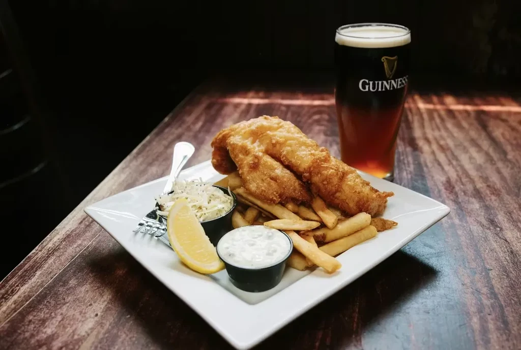 Fish and chips, coleslaw, tartar, lemon, and a Guinness stout.