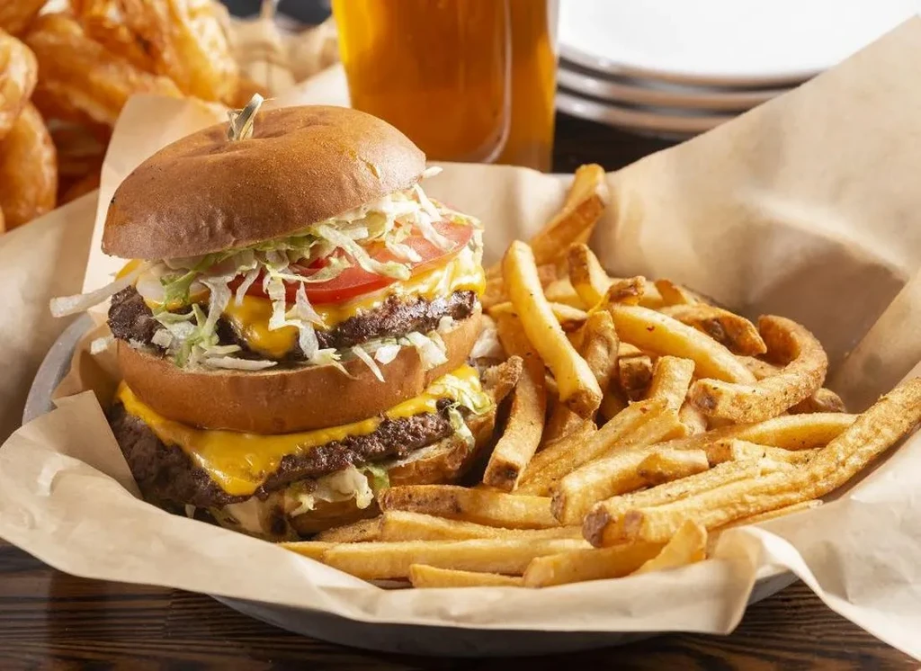 Double cheeseburger with melted cheese and golden fries in a basket.