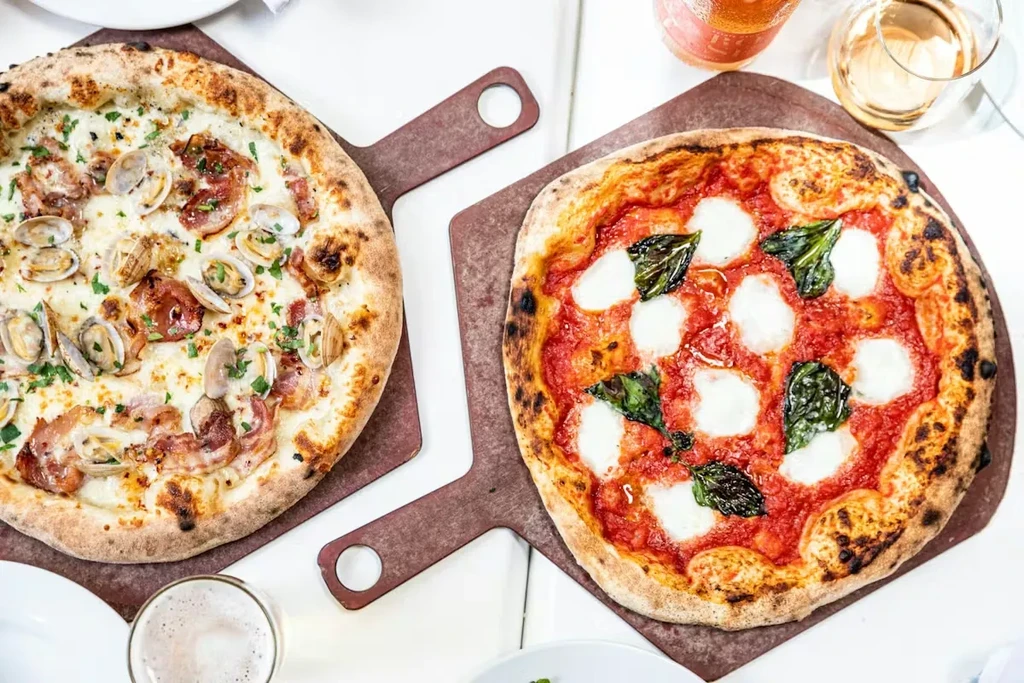 Two artisanal pizzas, clam and Margherita, with wine and beer.