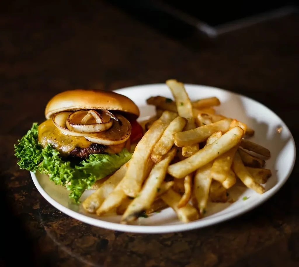 Cheeseburger with melted cheese, lettuce, onions, and golden french fries.