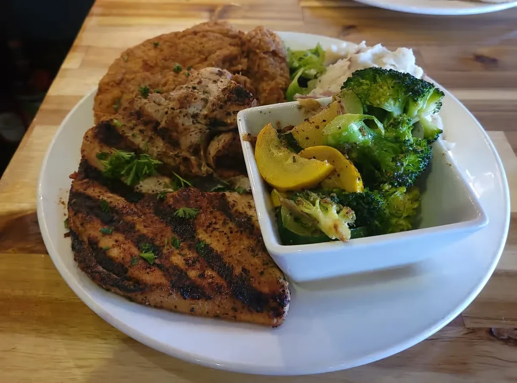 Overhead view of diverse meal with grilled meat, fried item, vegetables, potatoes.