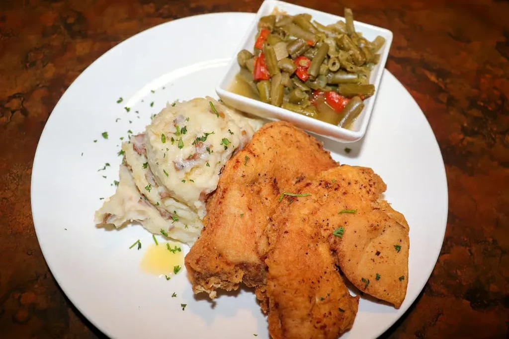 Close-up of fried chicken, mashed potatoes, and green beans on a plate.