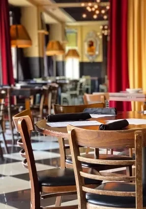Well-decorated restaurant interior: empty tables, checkered floor, red drapes, warm lights.