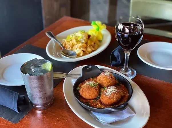 Table with fried spheres, macaroni cheese, Moscow Mule, red wine.