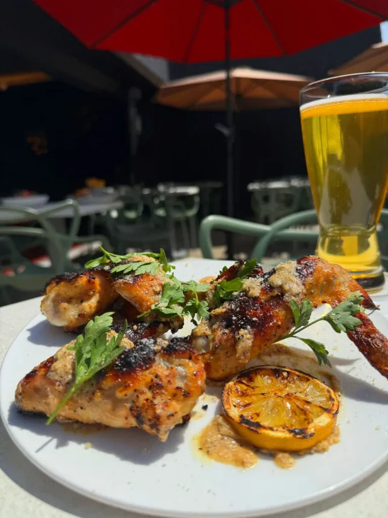 Grilled chicken, lemon, and beer on a sunny outdoor patio.