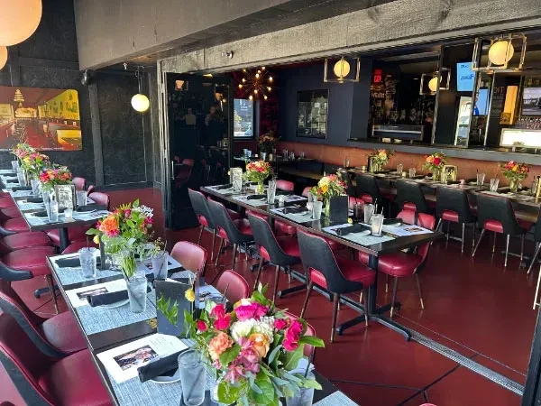 Modern restaurant interior with set tables, red floor, and stocked bar.