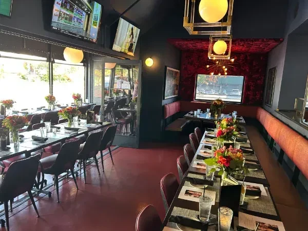 Dark modern restaurant interior with red accents and vibrant floral centerpieces.