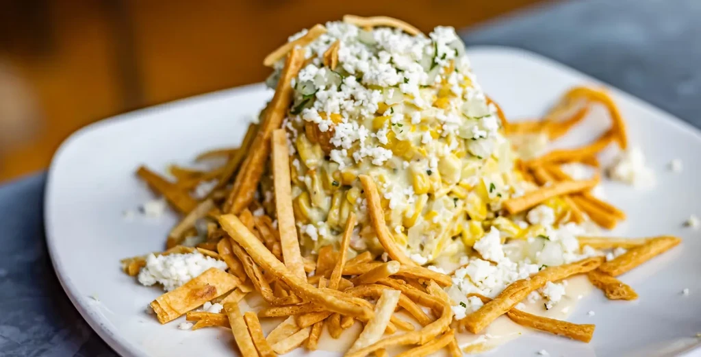 Creamy corn esquites topped with cotija cheese, herbs, and fried tortilla strips.