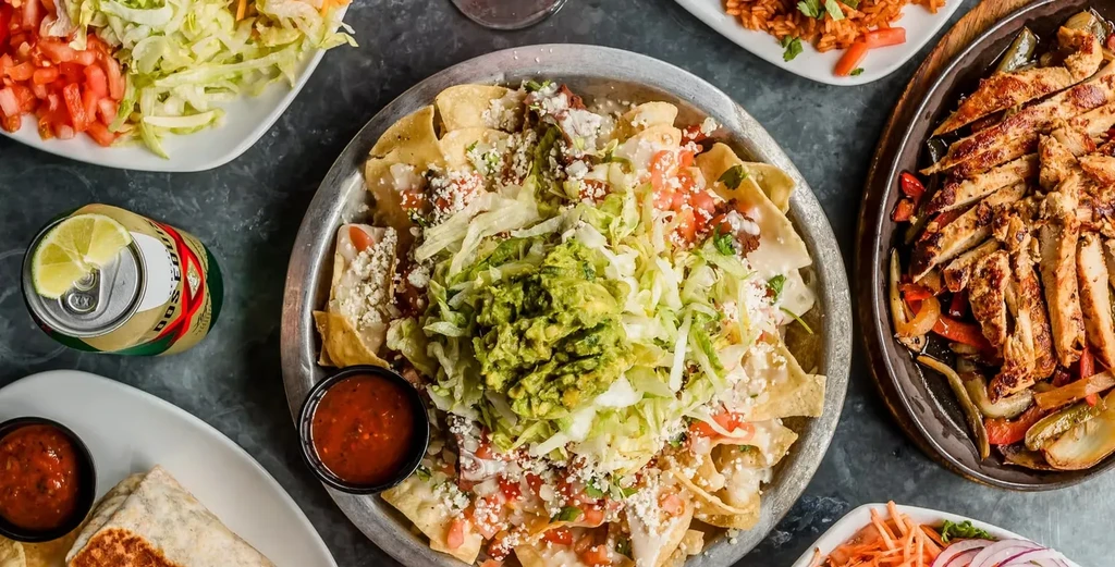 Overhead view of a vibrant Mexican food spread with nachos and fajitas.