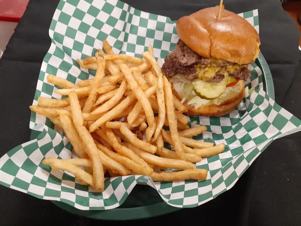 Double cheeseburger and crispy fries in a green checkered basket.
