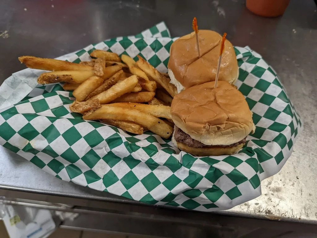 French fries and two sliders on a checkered paper-lined tray.