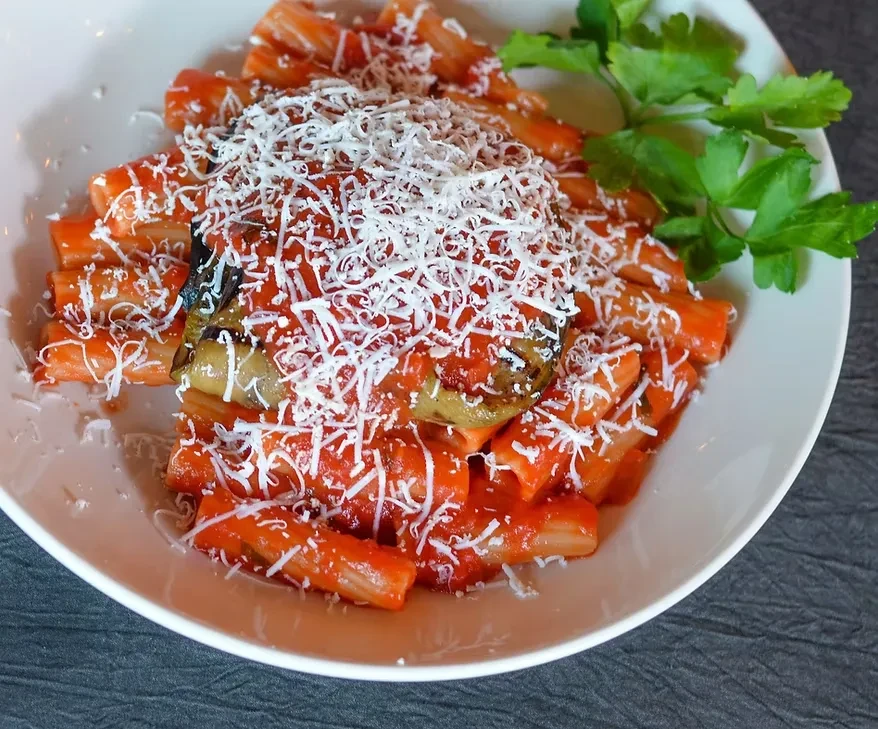 Top-down rigatoni with tomato sauce, eggplant, cheese, and parsley.