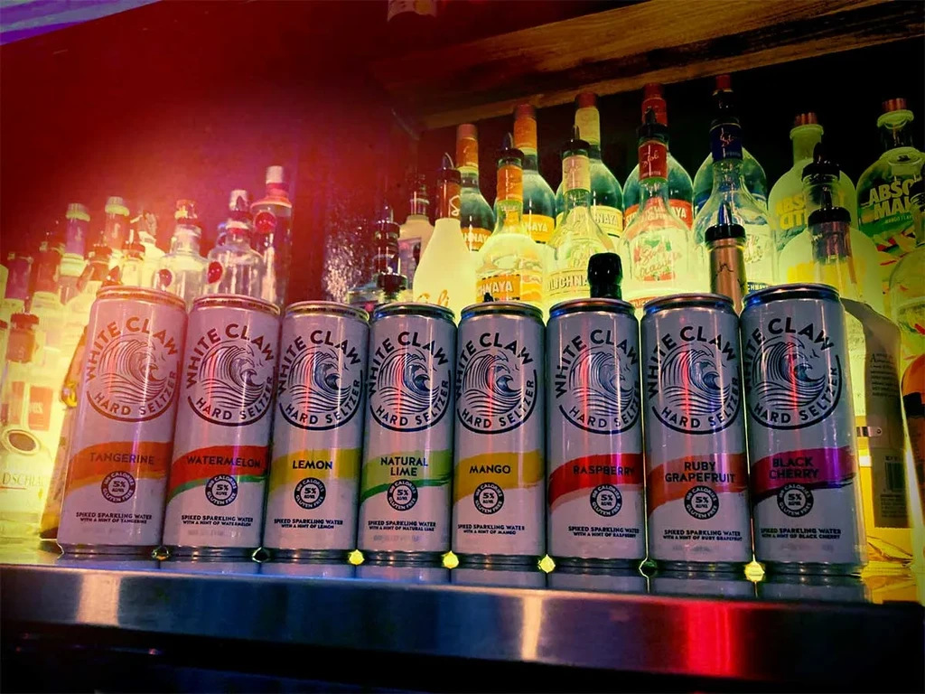 White Claw hard seltzer cans line a dimly lit bar counter.