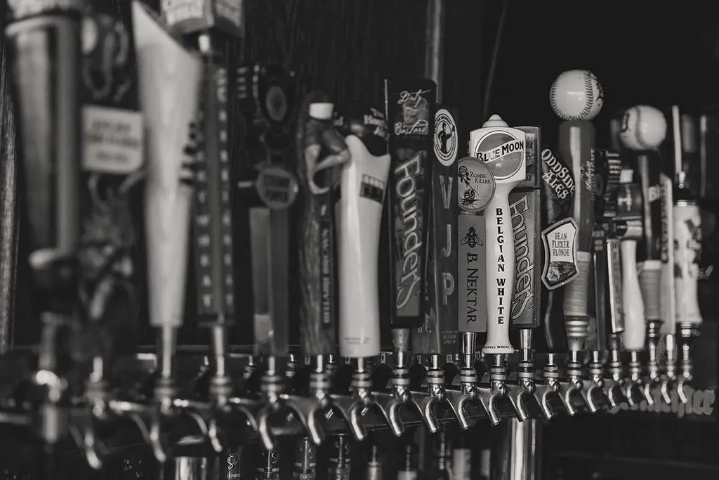 Black and white photograph showing a row of various beer tap handles.