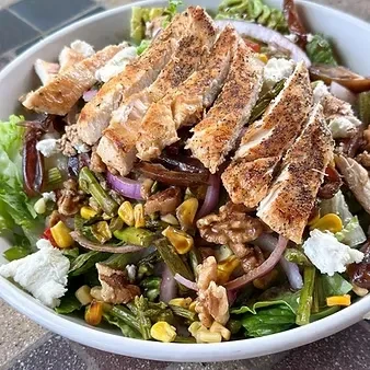 Overhead grilled chicken salad with mixed greens, corn, cheese, walnuts.