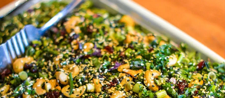 Vibrant green salad with cashews, cranberries, and sesame seeds.