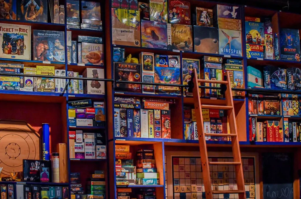 Floor-to-ceiling dark blue shelves packed with board games and a ladder.