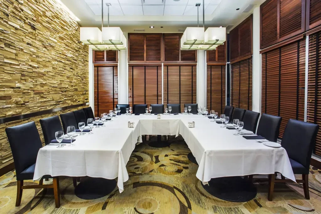 Private dining room with U-shaped table, set for multiple guests.