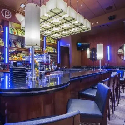 Modern bar with blue LED lights, spirit bottles, and bar stools.