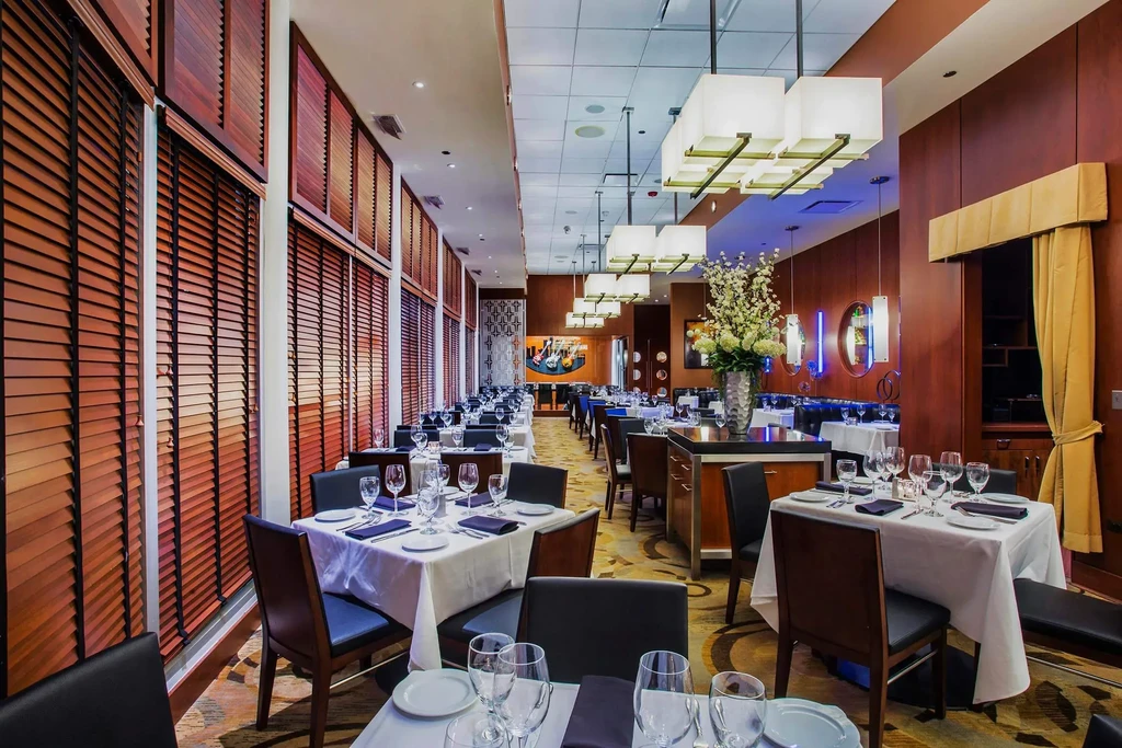 Empty, upscale restaurant dining room with many tables set for service.