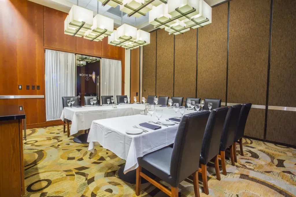 Upscale private dining room with U-shaped table and elegant place settings.