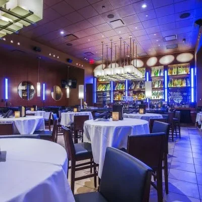 Modern, empty restaurant and bar interior with blue accent lighting.