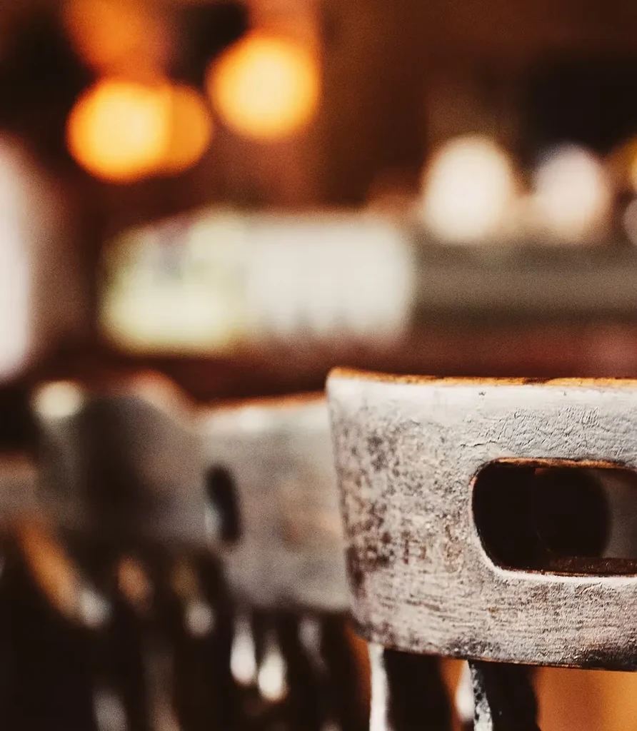 Close-up of distressed industrial bar stools, warm bokeh background.